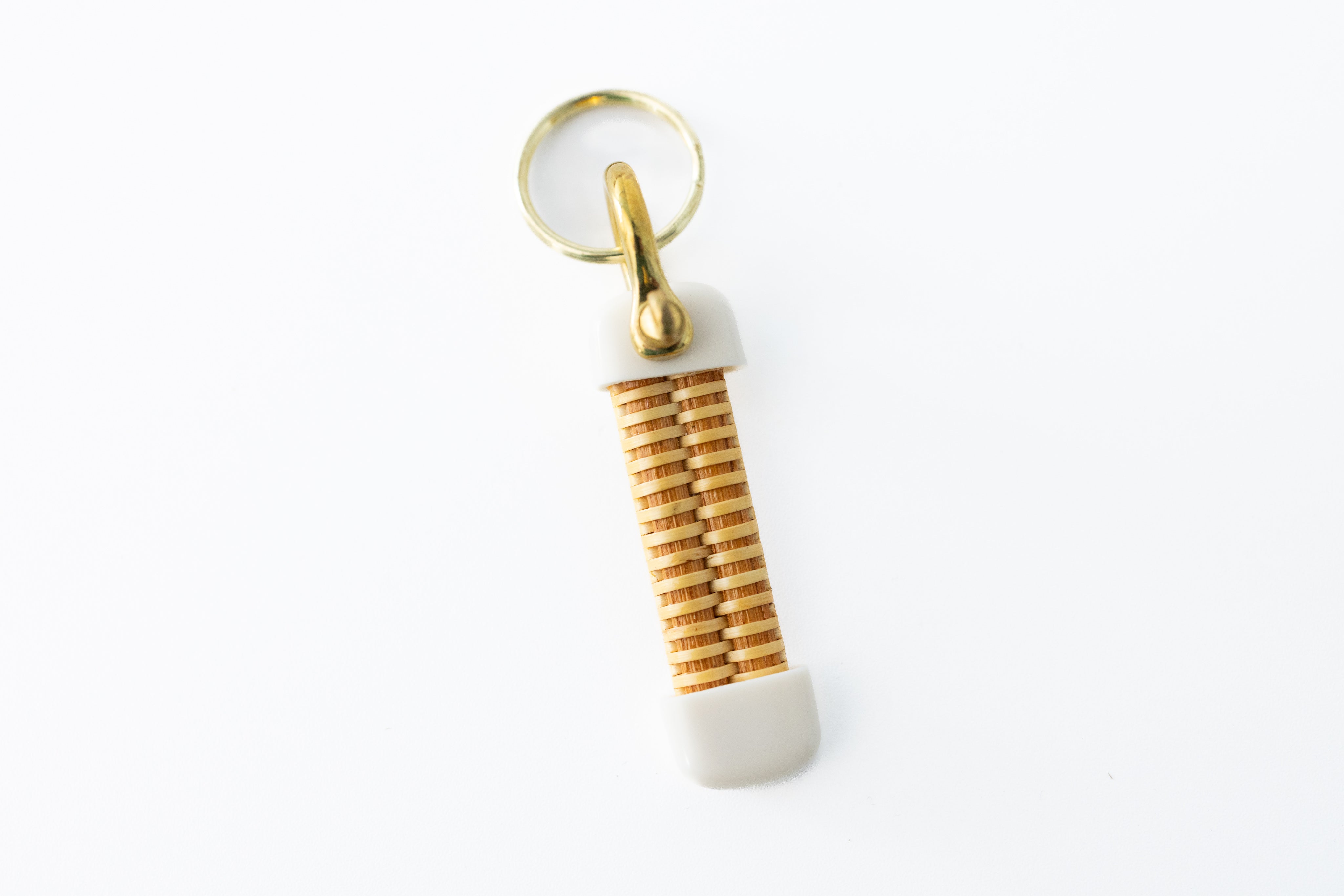 A small Nantucket basket keychain with a beige and brown color scheme, featuring a brass shackle.
