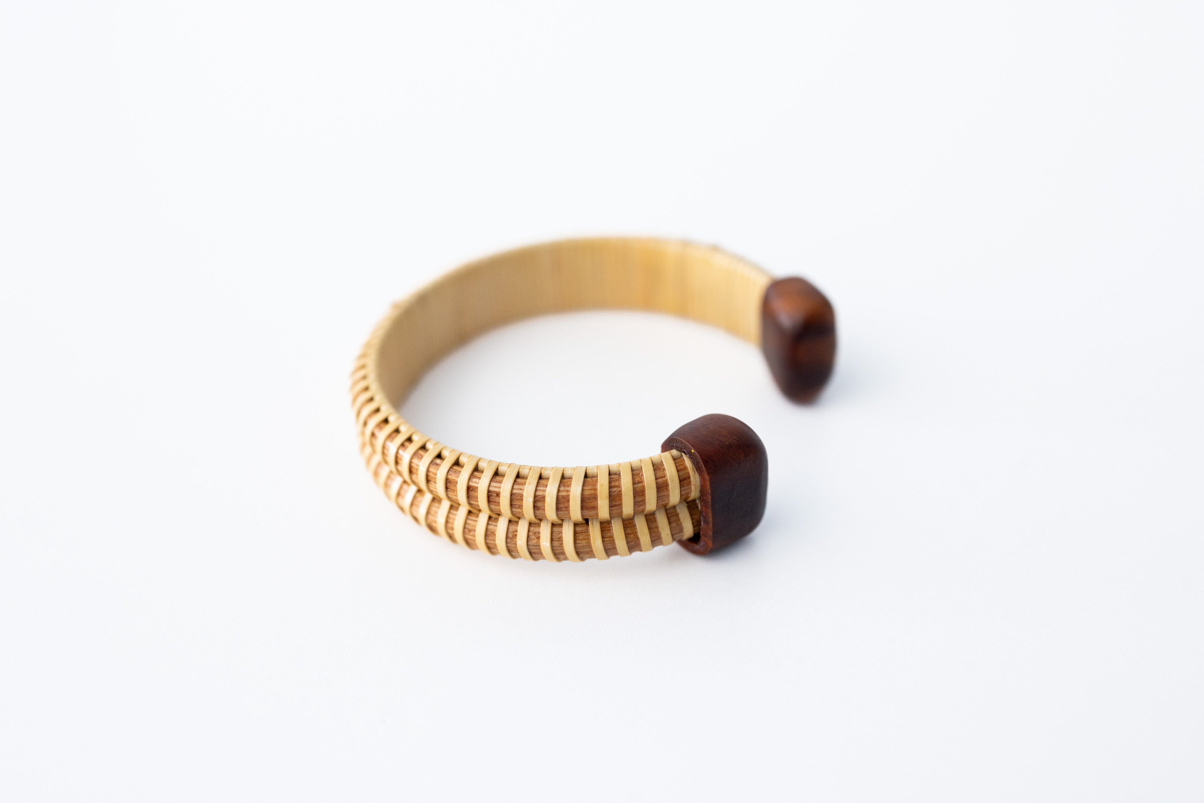 A beige-colored double stave Nantucket basket cuff bracelet with cherry hardwood end caps on a white background.
