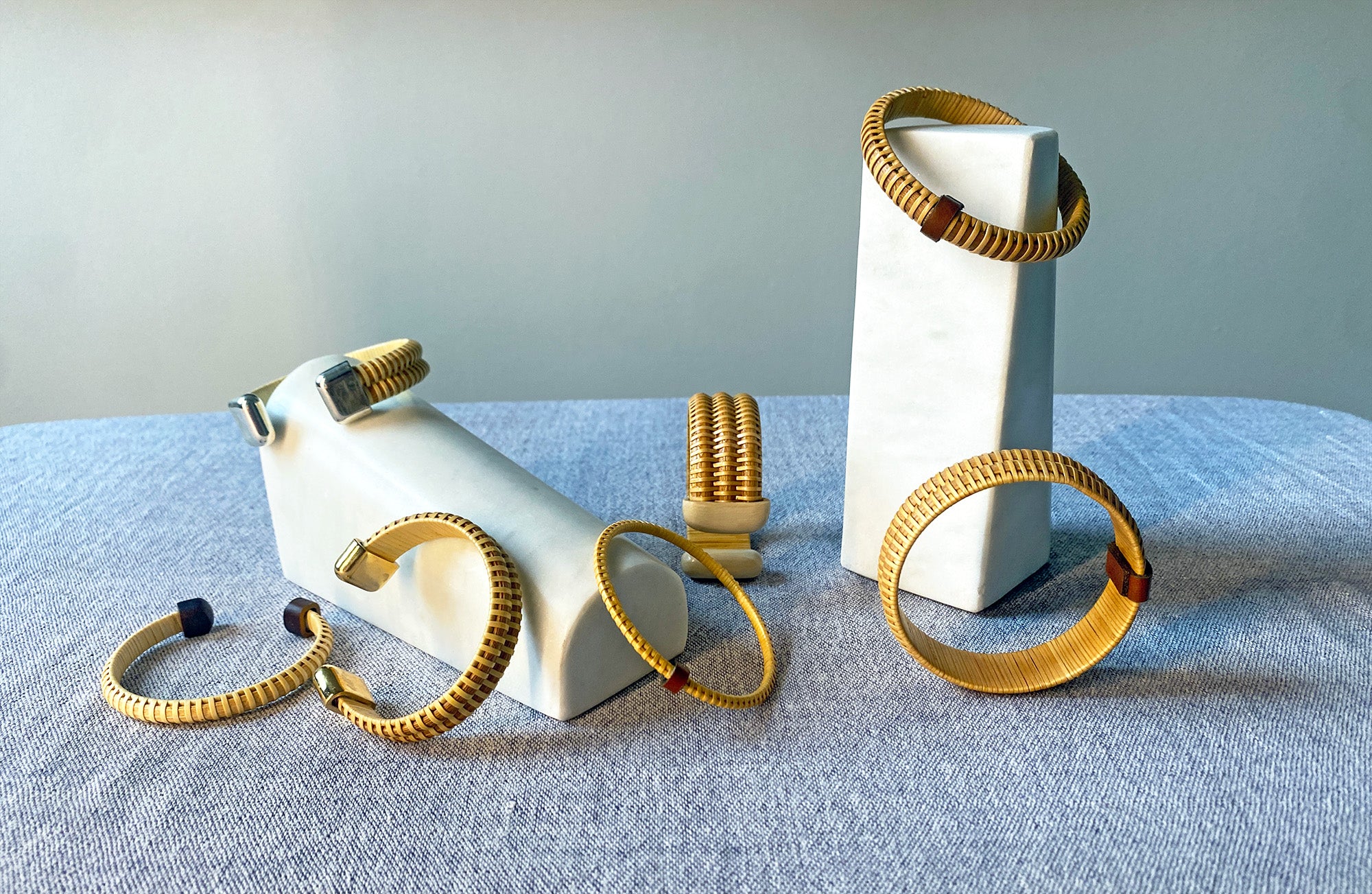 Collection of bracelets and cuffs displayed on a white stand against a gray background