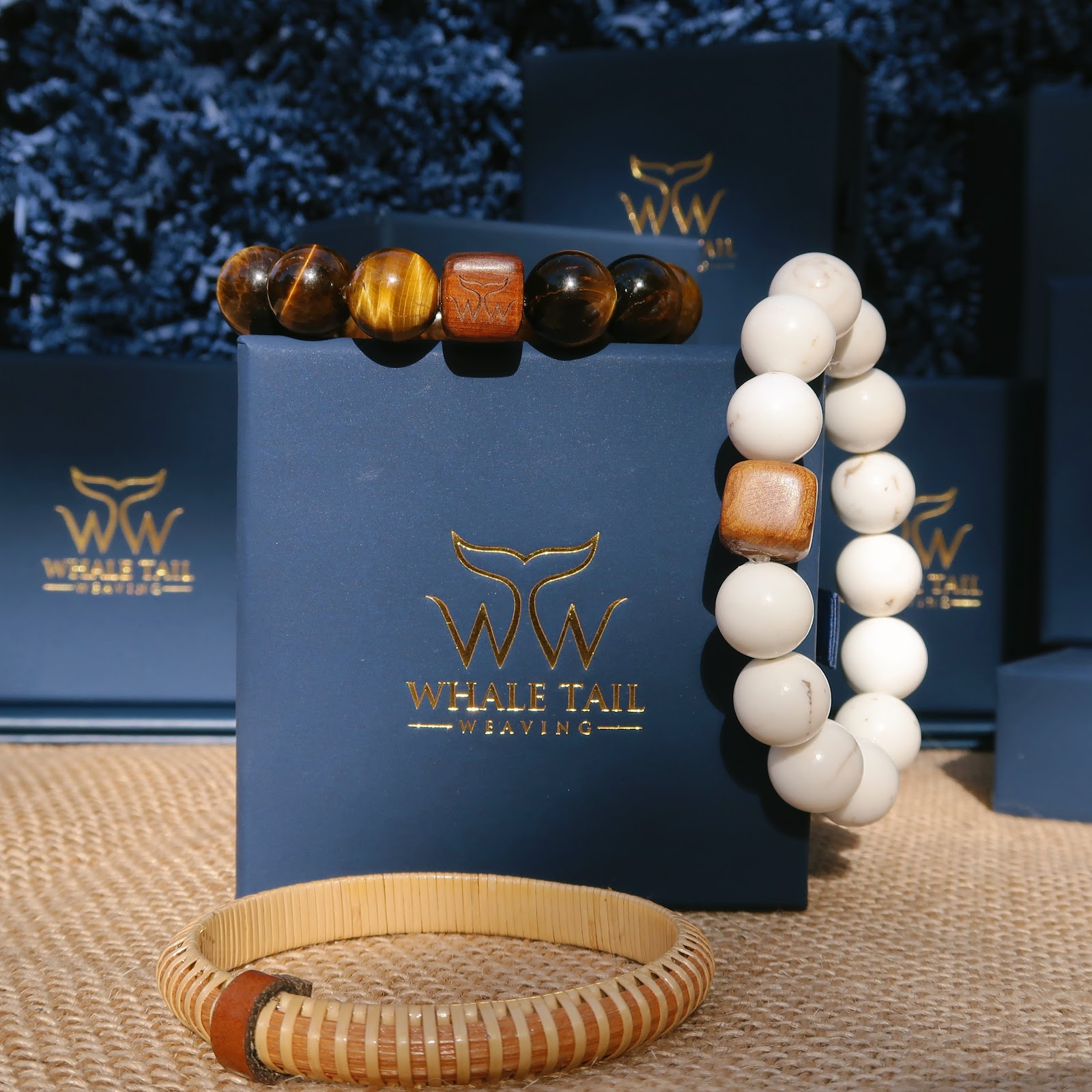 Three nautically inspired bracelets lay on top of and in front of a Whale Tail Weaving gift box.